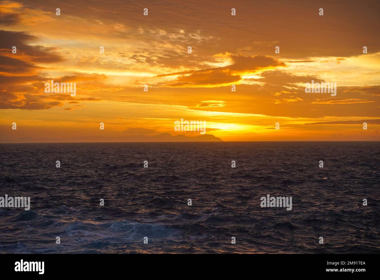 Sunset from Menorca, Mallorca can be seen at the horizon, Balearic islands, Spain. Stock Photo