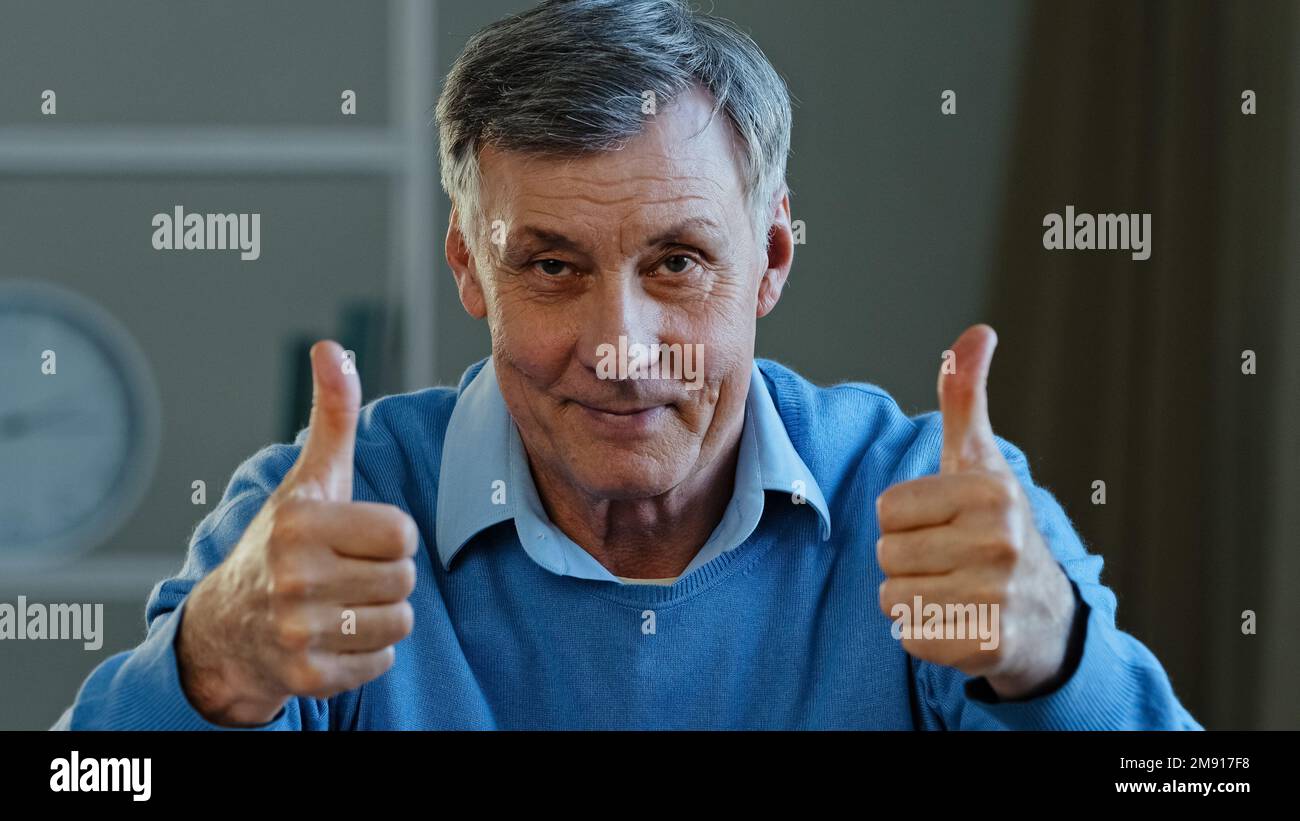 Close up success happy mature elderly old Caucasian man showing two thumbs up smiling pensioner looking at camera demonstrate like good idea Stock Photo