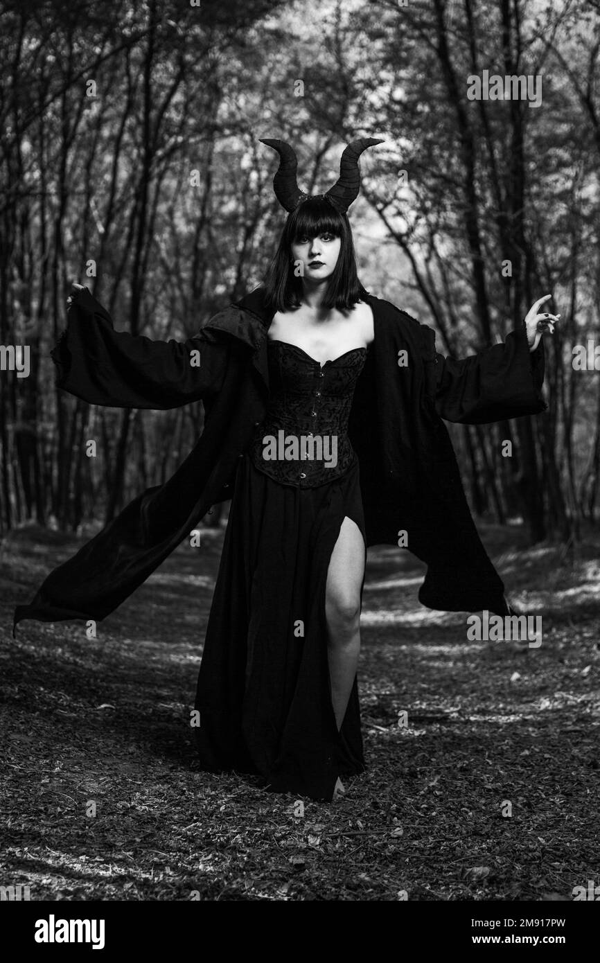 A vertical shot of a gothic girl with Maleficent horns posing in a mystic forest Stock Photo