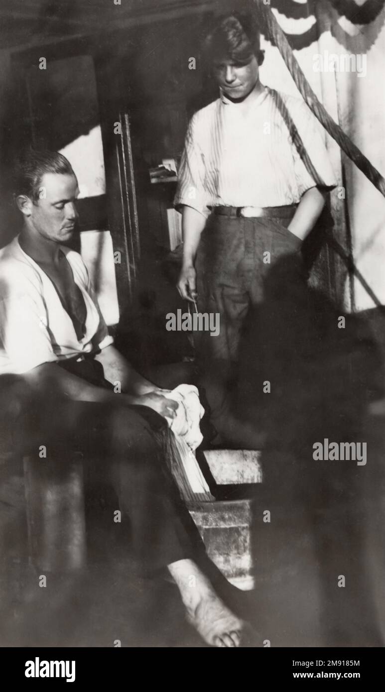 One sailor doing laundry while another watches, on the deck of the four