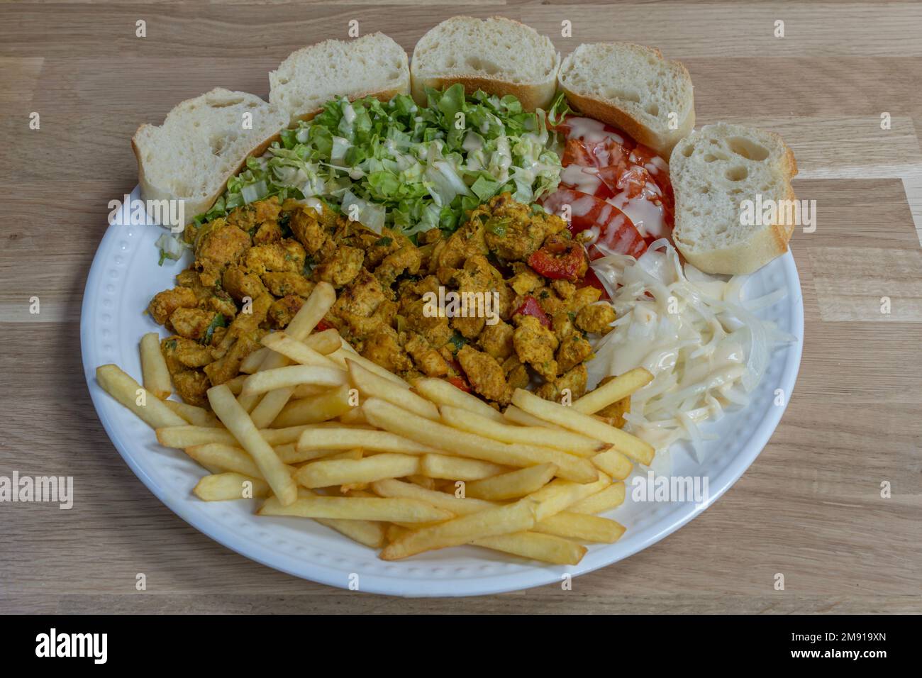 Bistro dishe culinary Still Life. Oriental Chicken with salad, tomato accompaniement onion, french fries and slice of bread Stock Photo