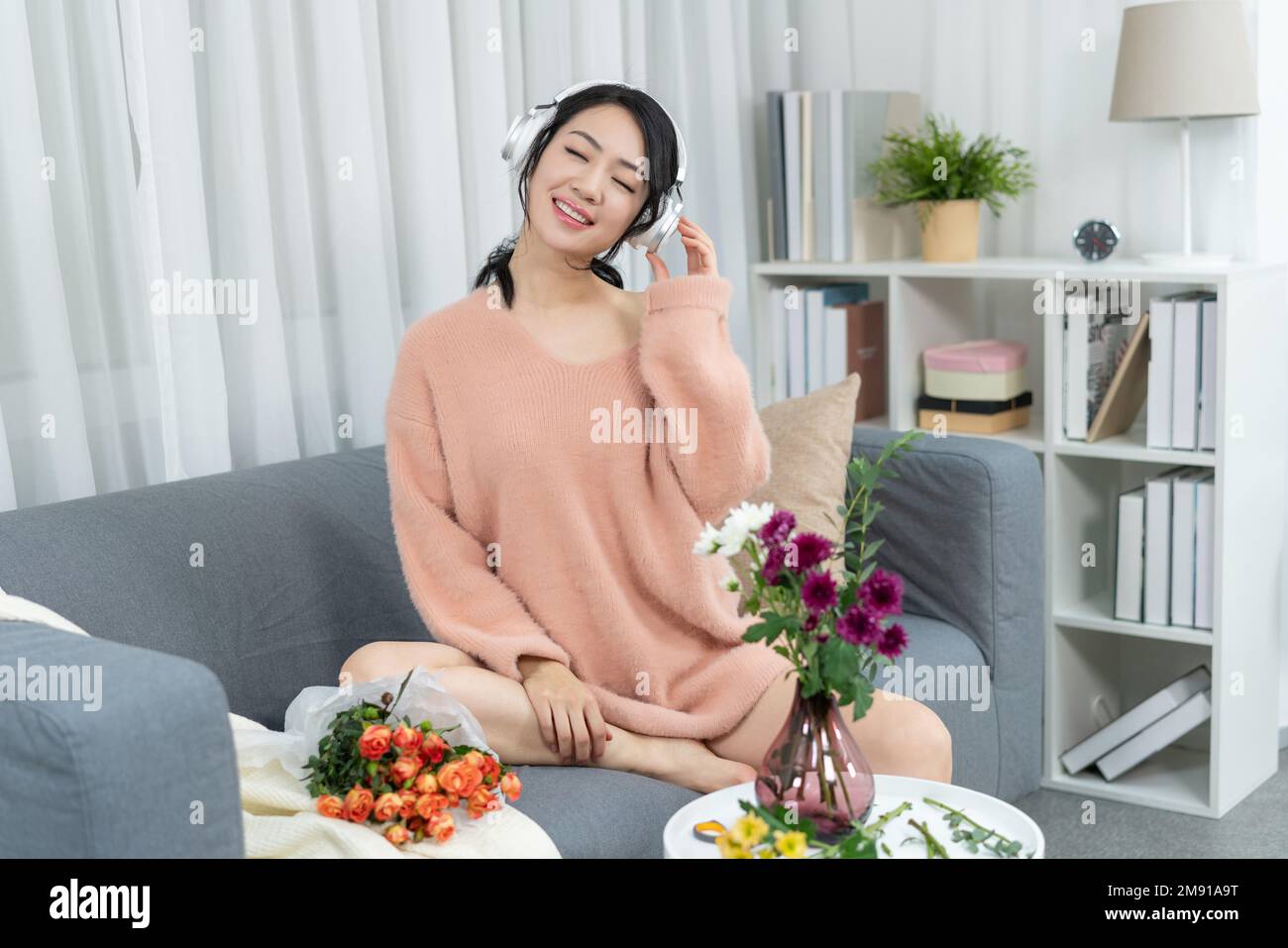 Young woman sitting on the sofa listening to music Stock Photo - Alamy