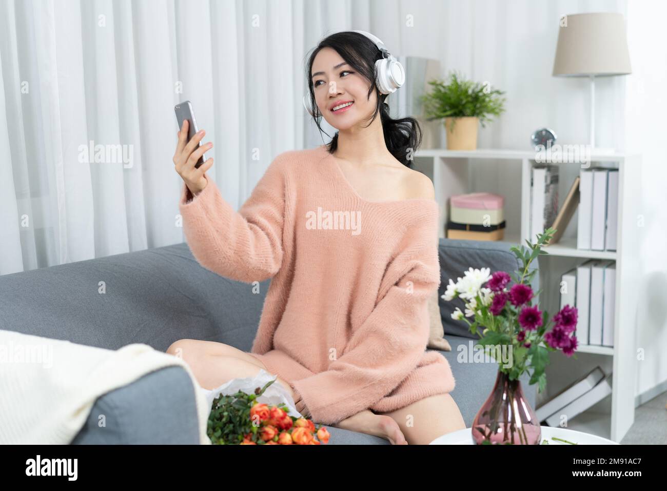 Young woman sitting on the sofa listening to music Stock Photo - Alamy