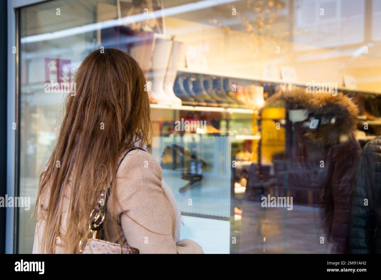 Symbol image shopping: Young woman standing in front of a shoe shop (Model released) Stock Photo