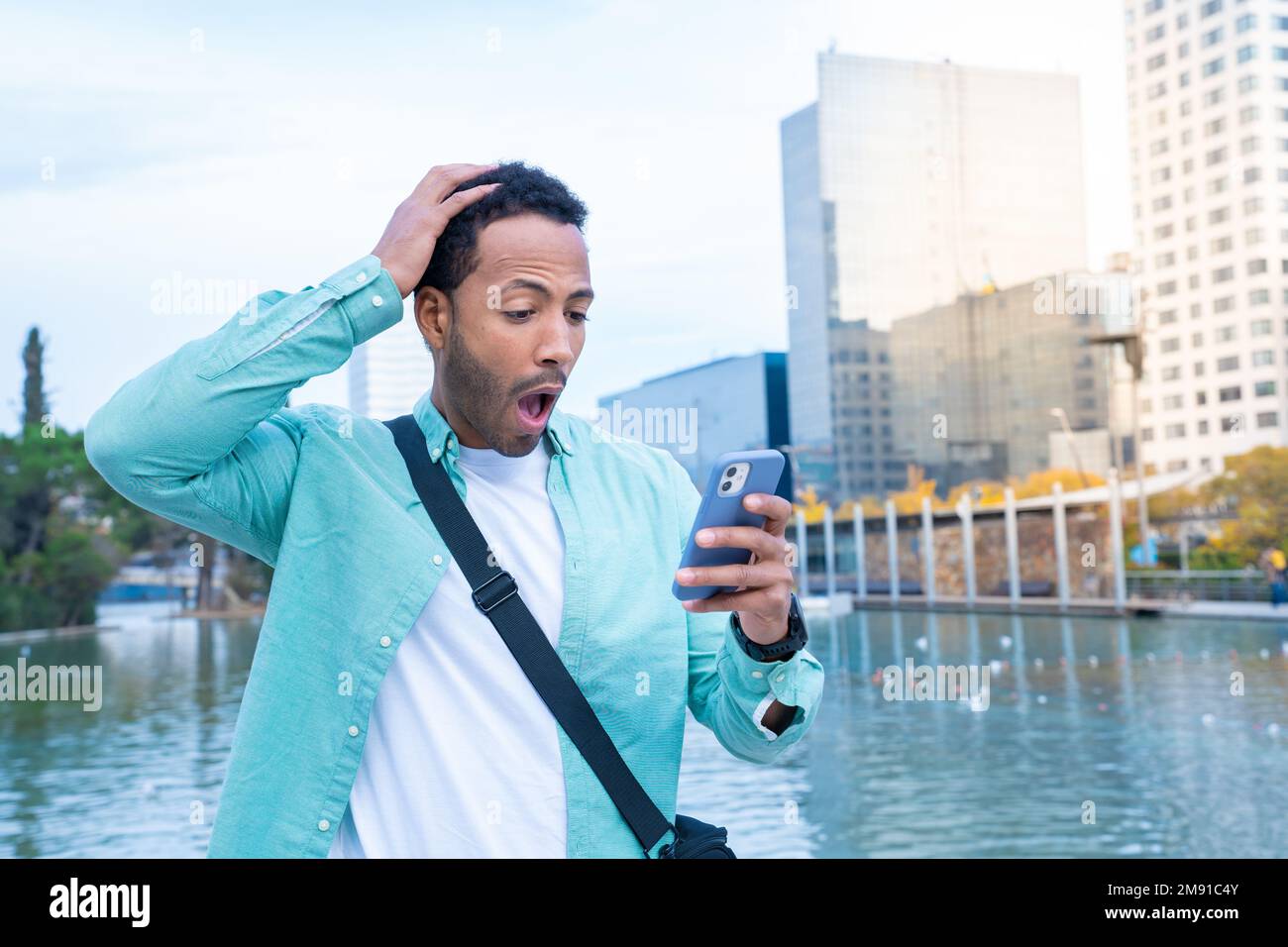 Young black man in the street looking at the phone with a surprised expression. Stock Photo