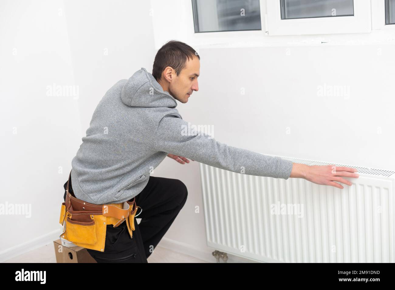 Man is repairing radiator battery in the room. Maintenance repair works