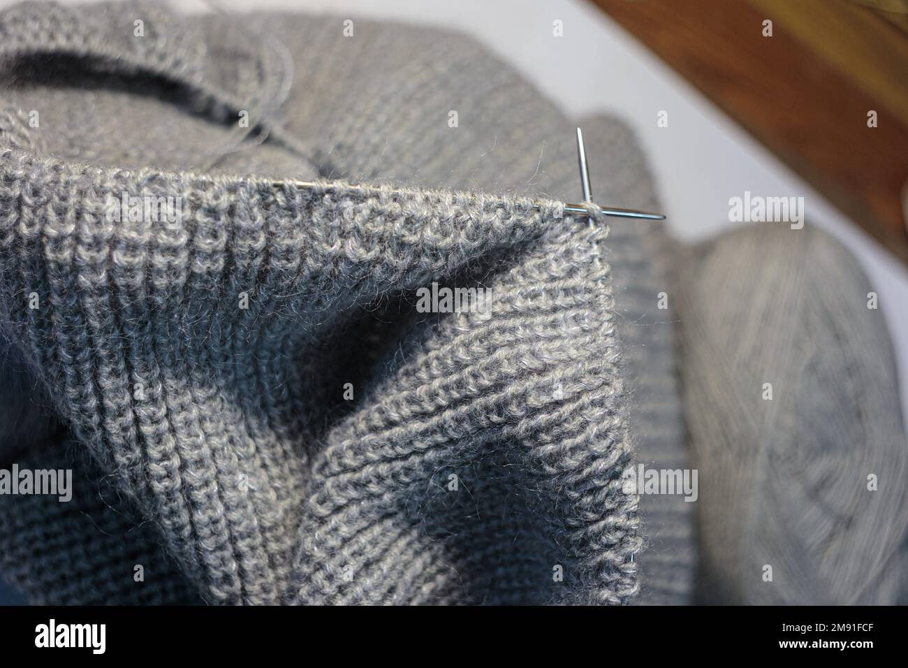 Knitting the clothes using circular needles. On grey blurred background. Top view Stock Photo