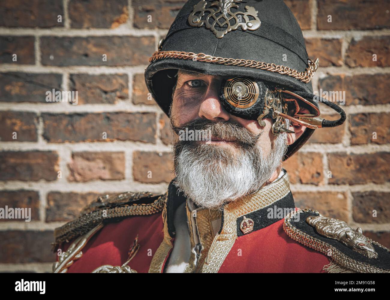 Portrait of an distinguished looking man with a grey beard. He is wearing a military uniform and a retro futuristic steampunk monocle. Stock Photo