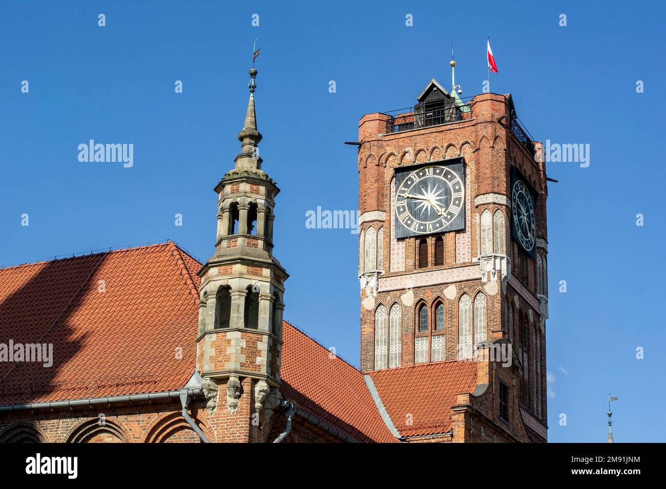 Torun town hall of Ratusz Staromiejski clock tower from 18th century with Polish flag in Poland Stock Photo