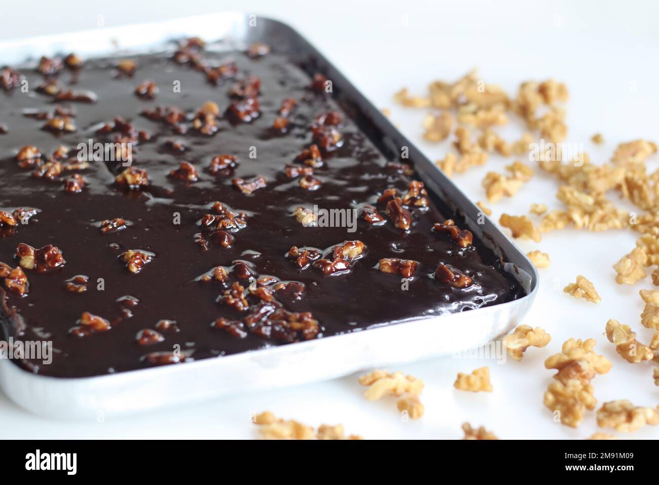 Texas Sheet Cake in baking pan. It is a large, thin chocolate cake topped with a rich chocolate walnut frosting. It's moist and fluffy, with a hint of Stock Photo