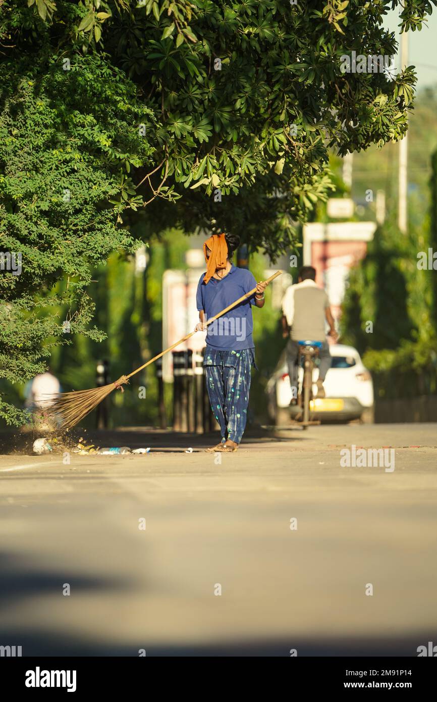 January, 2022 , A female cleaner worker brooming or sweeping with a broom to the road of raipur at morning, Sweeper sweeping the road and cleaning wit Stock Photo