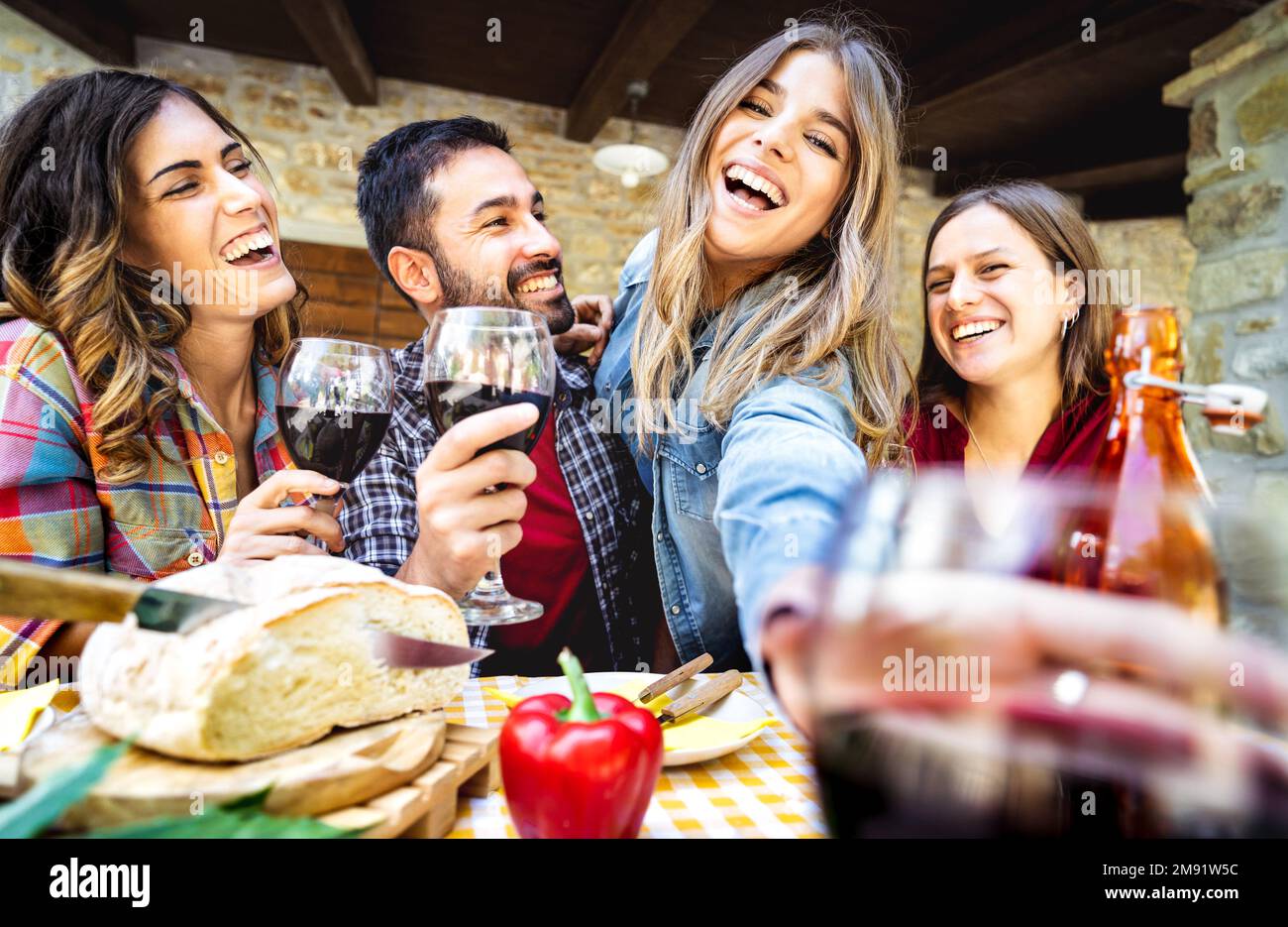Young people having fun drinking wine out side at farm house bar patio