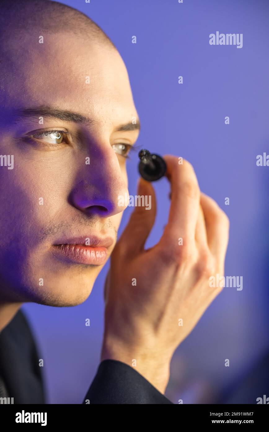 Close up face of a young homosexual man applying mascara. High quality photo Stock Photo