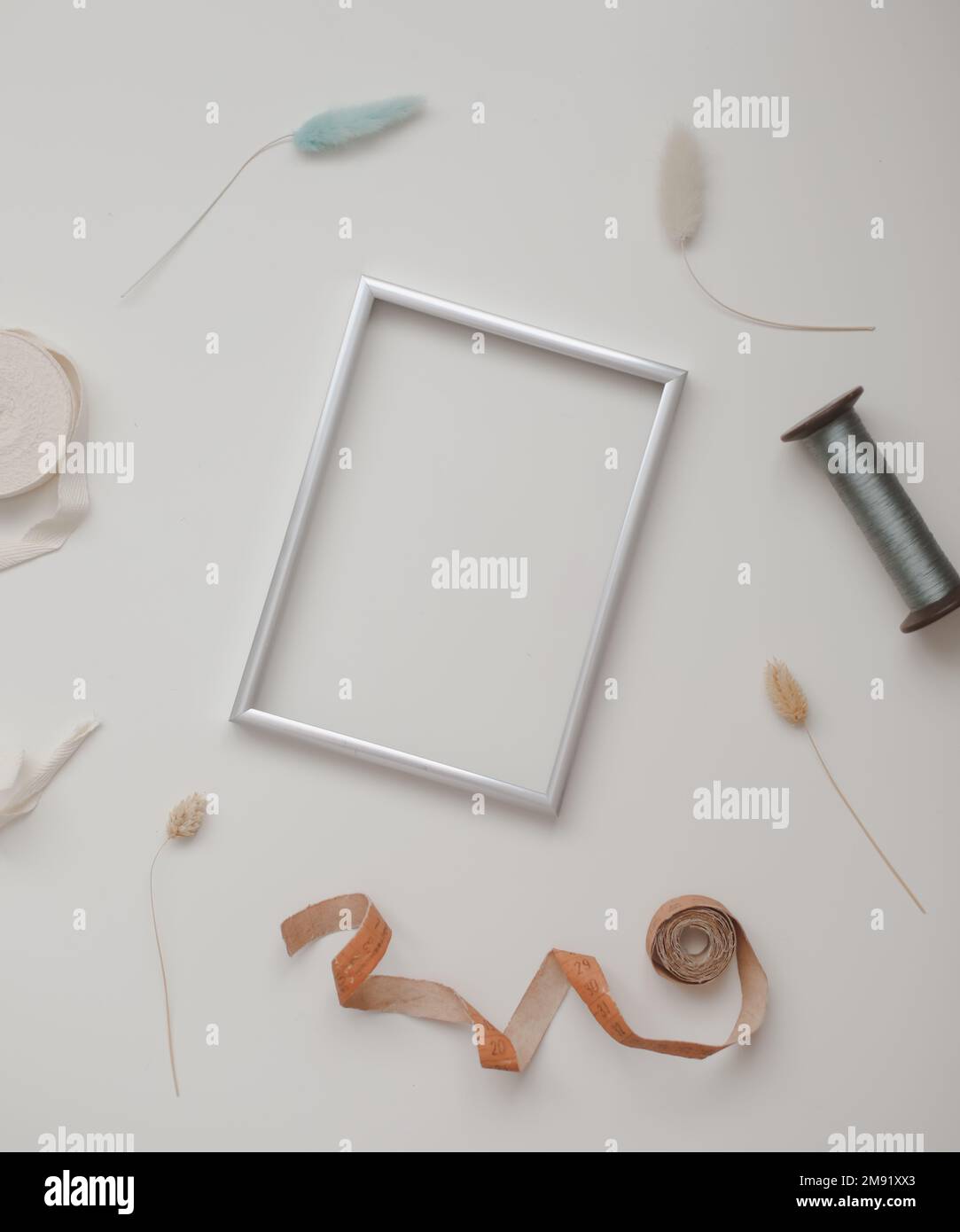 minimal mockup with blank frame with sewing thread and sewing items on white background, flatlay, top view, copy space Stock Photo