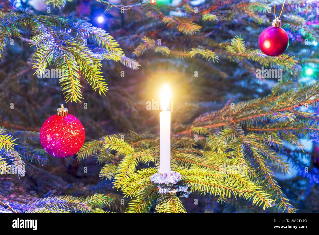 Burning candles and Christmas decorations in red color hung on a