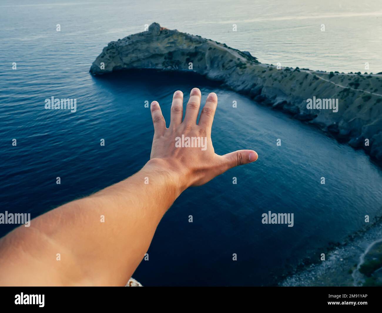 hand of a male tourist on the background of the sea. Symbolizes freedom, unity and protection of nature Stock Photo
