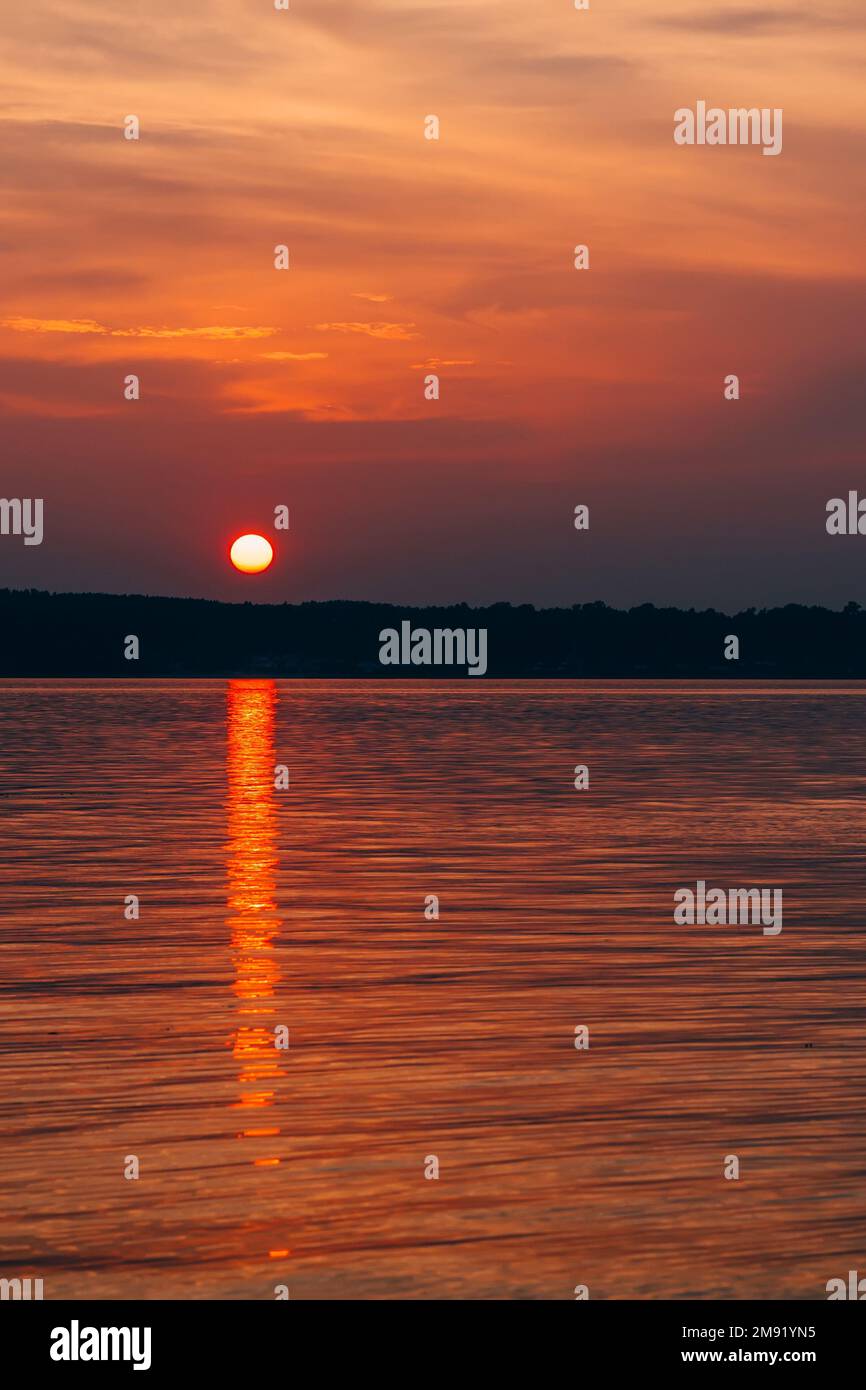sunset on a summer evening with a big sun over the water of the sea ...