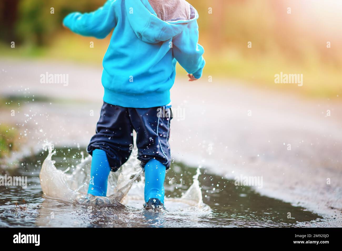 Small child jumping through puddles in nature in spring Stock Photo - Alamy