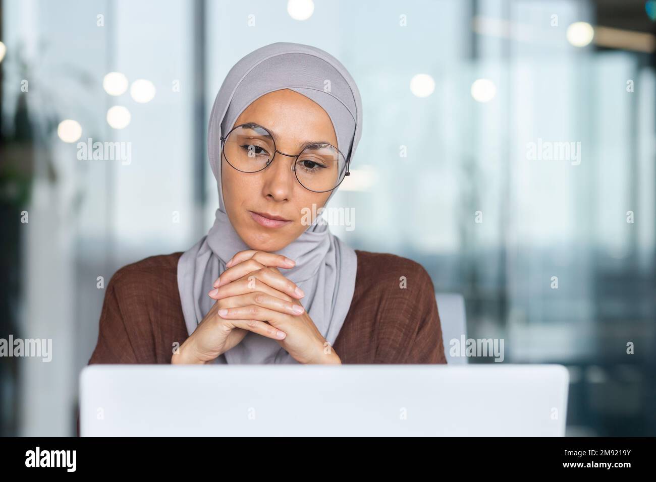 Serious bored businesswoman inside office, muslim woman in hijab