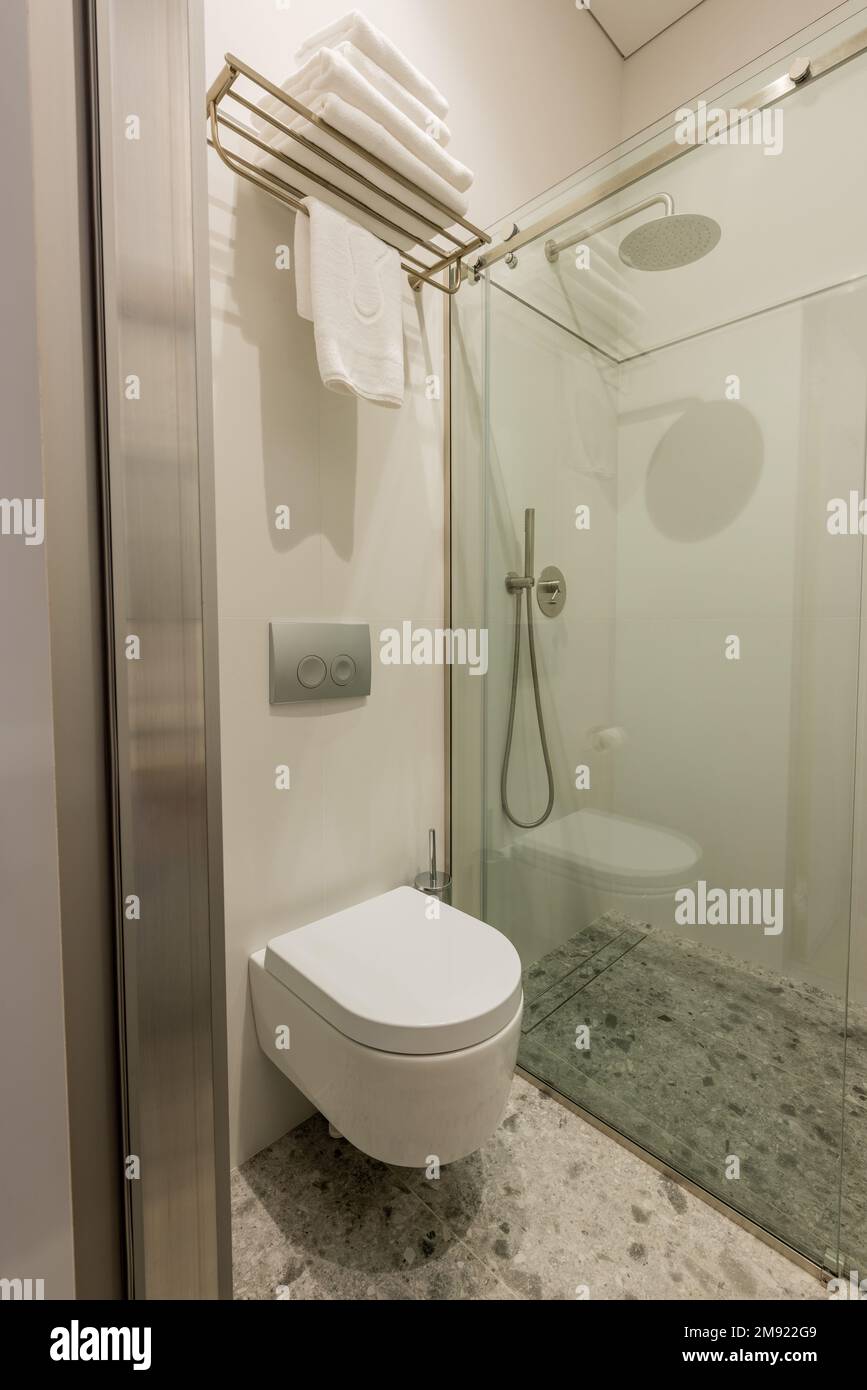 interior of modern white bathroom with white toilet near glass door and ...