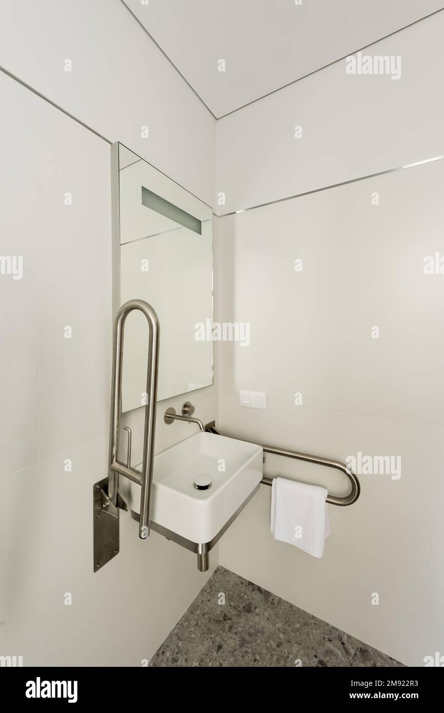 interior of white bathroom with sink and mirror for disabled people in