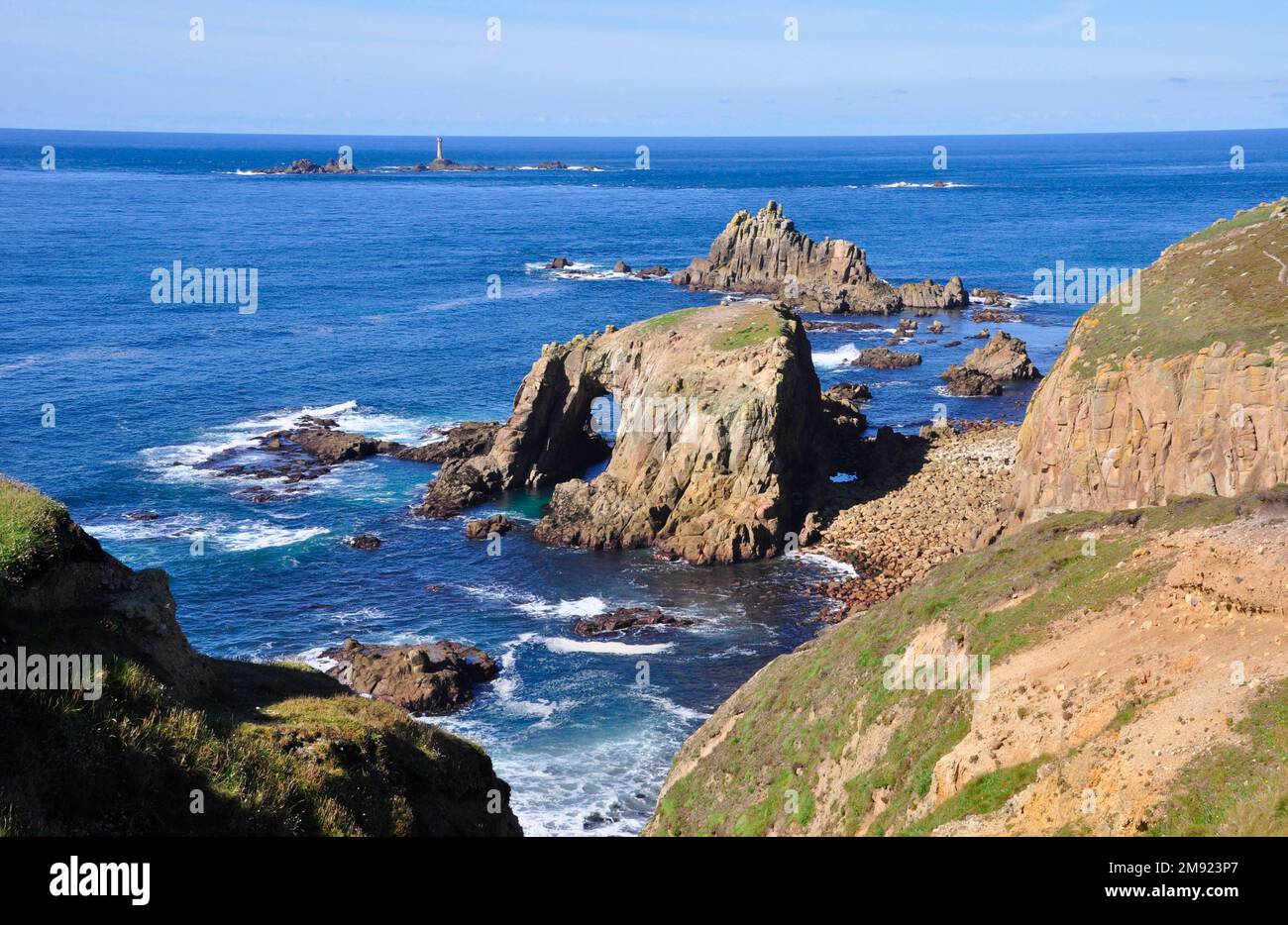 View towards the Longships lighthouse off Lands End in Cornwall, from the South West Coast path with Enys Dodnan and the Armed Knight rocks in the for Stock Photo