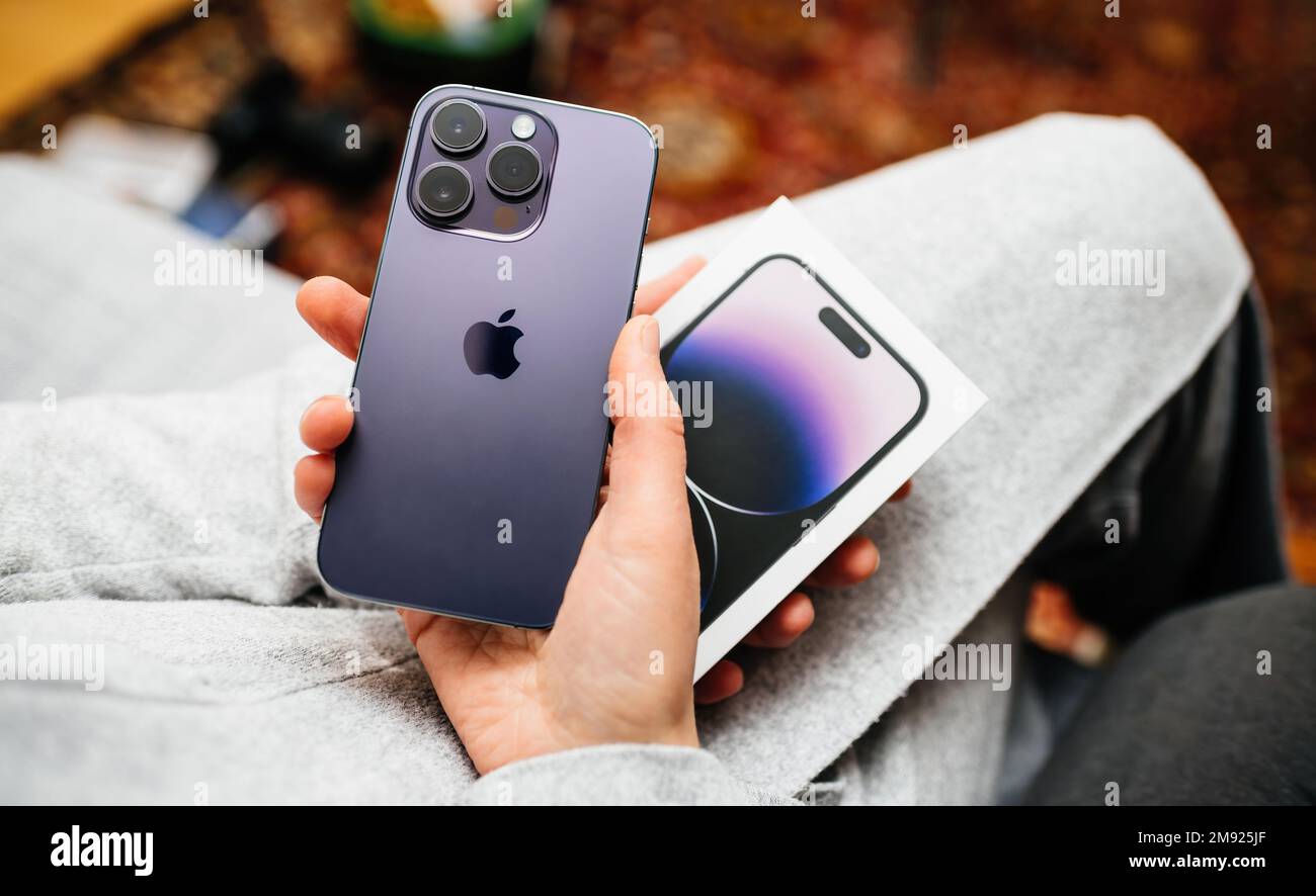 London, United Kingdom - Sep 28, 2022: POV woman hand holding unboxing the package showing new Deep Purple Apple iPhone 14 Pro Max the sixteenth-generation flagship iPhones with no SIM cards triple rear professional lenses Stock Photo