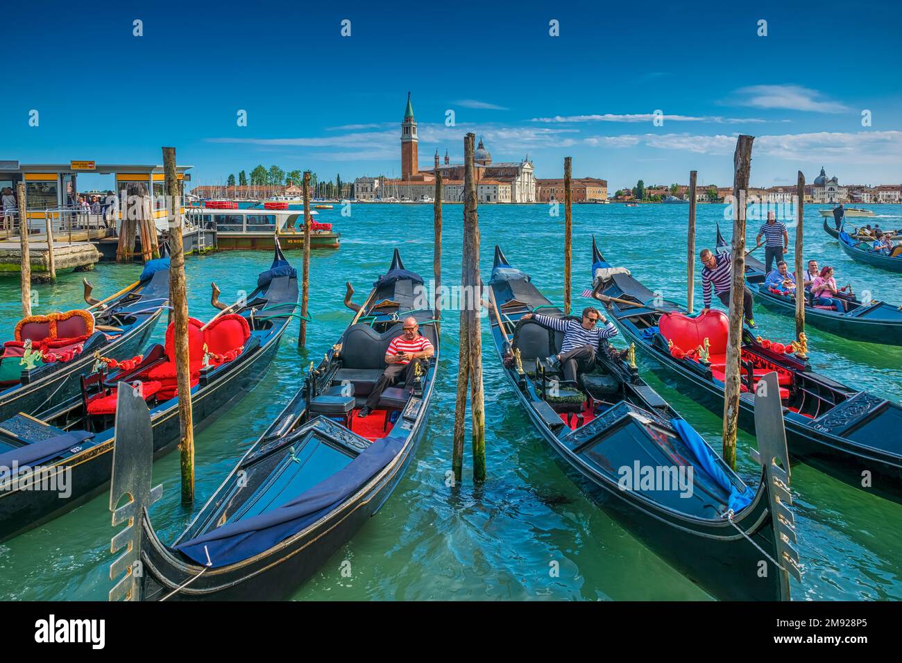Two 'Gondolieri' waiting for customers in Venice, Italy, the island of San Giorgio di Maggiore can be seen in the background. Stock Photo