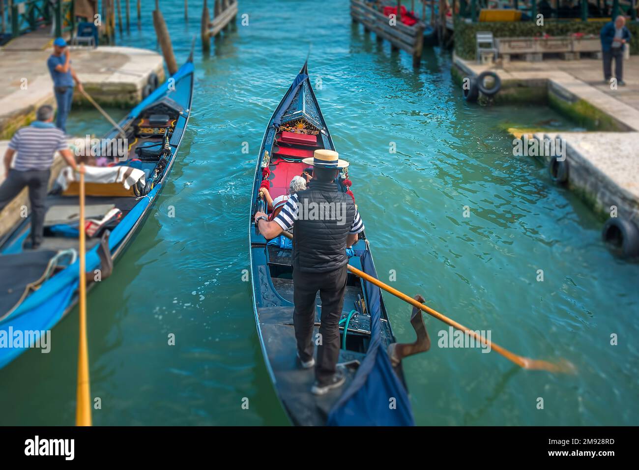 A Gondoliere is taking his guest around Venice on a small side canal passing another Gondola in Venice, Italy Stock Photo