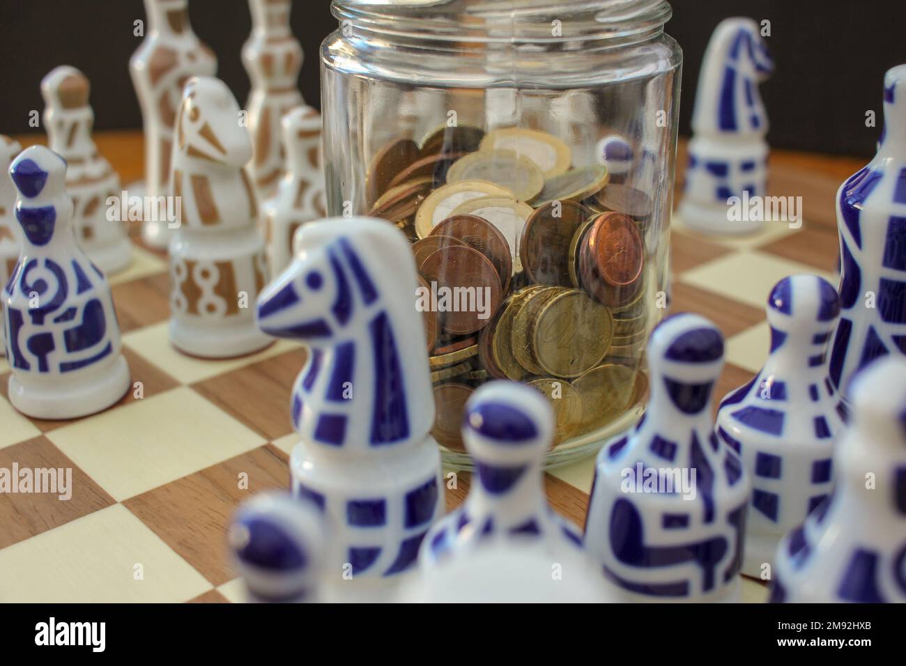 euro coins in a glass jar on the chessboard among chess pieces Stock Photo