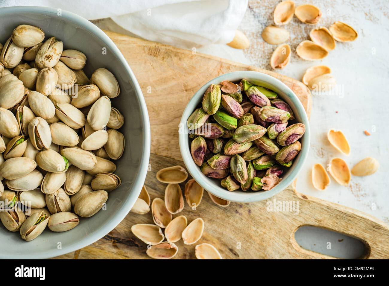 Ceramic bowl with organic pistaschio nuts on white wooden table