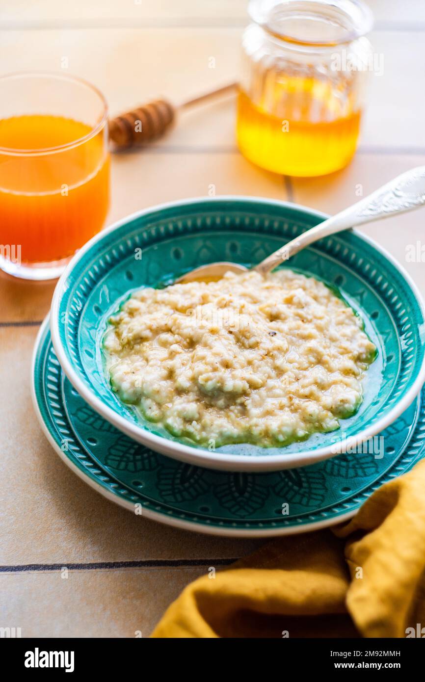 From above healthy breakfast with oat porridge and honey on tiled ...