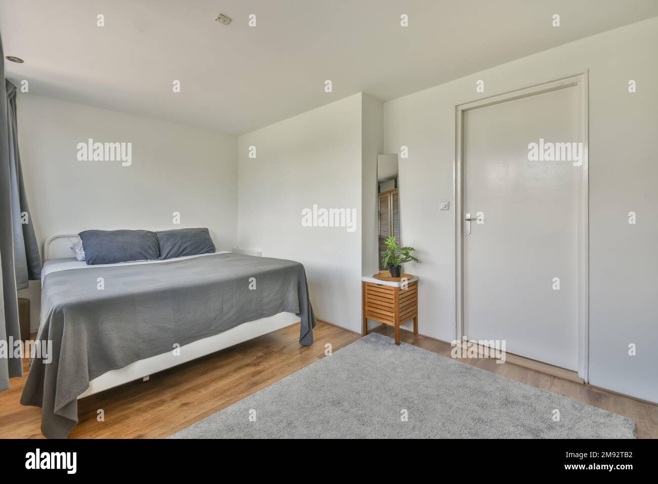 Comfortable bed next to a door and wooden floor Stock Photo - Alamy