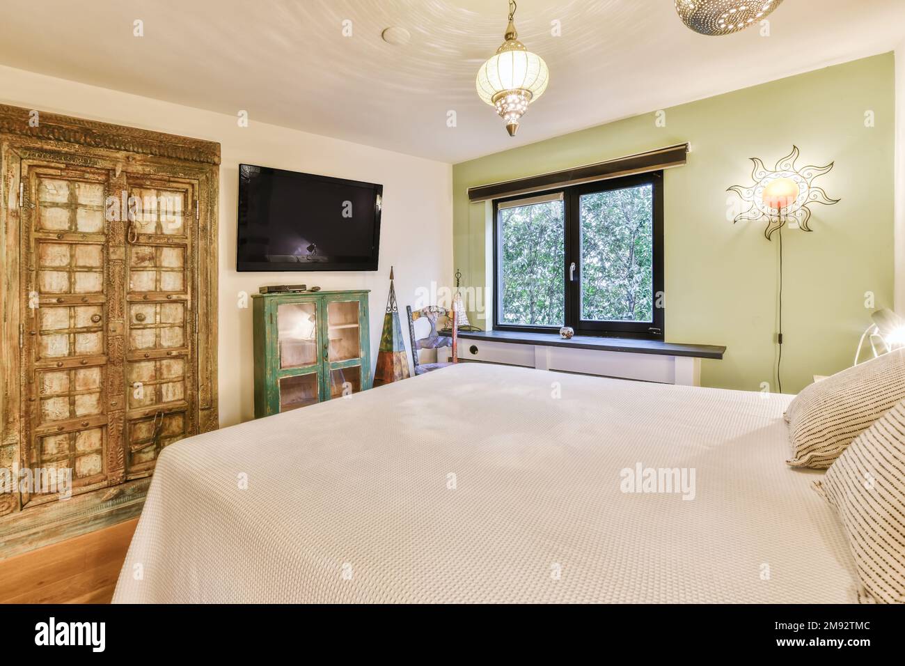 Interior of bedroom in Moroccan style with soft double bed near green