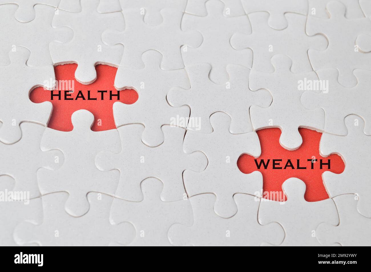 A white puzzle with two black parts written with HEALTH and WEALTH on a red  background Stock Photo - Alamy