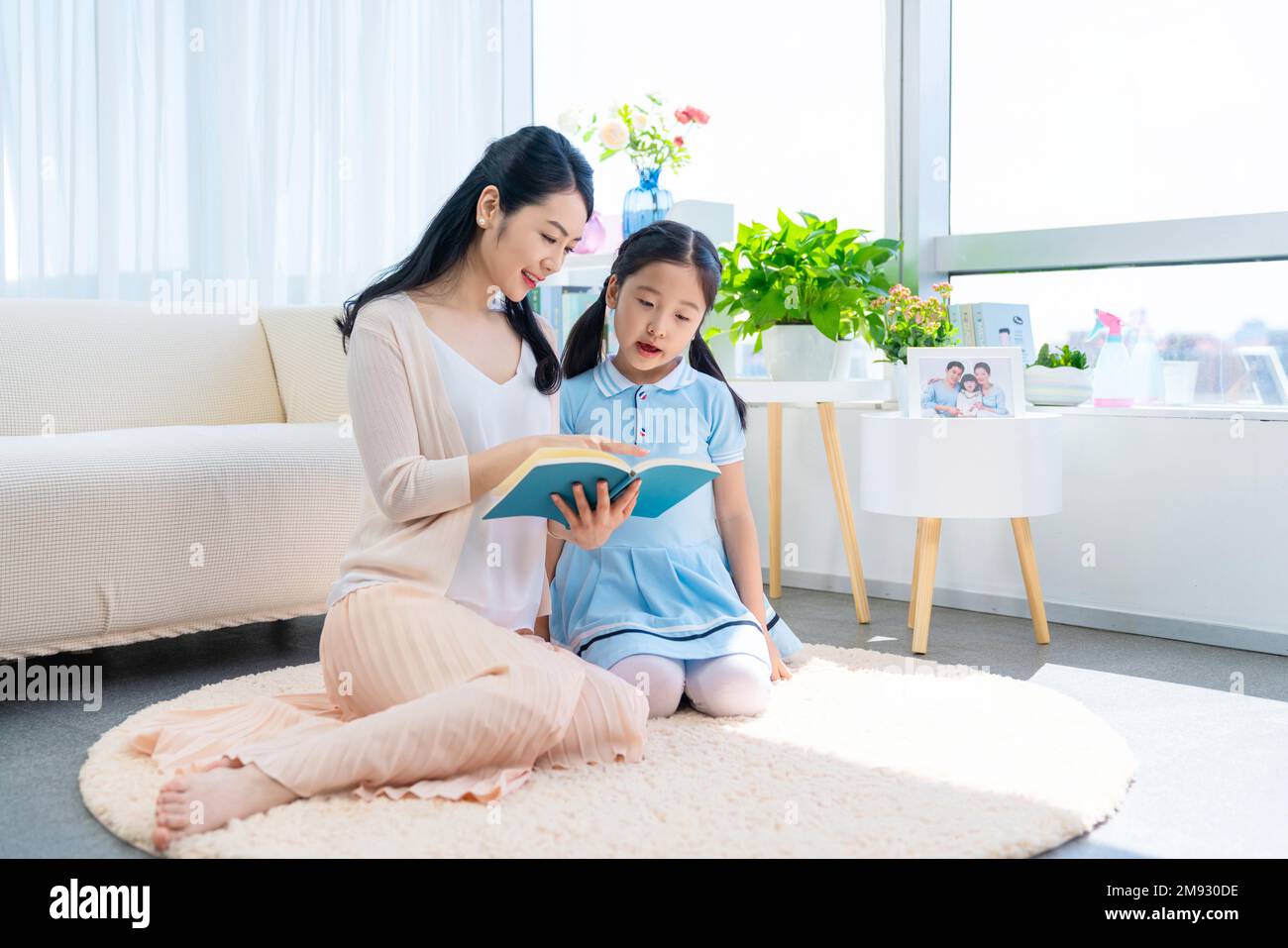 The little girl and her mother read a book together Stock Photo