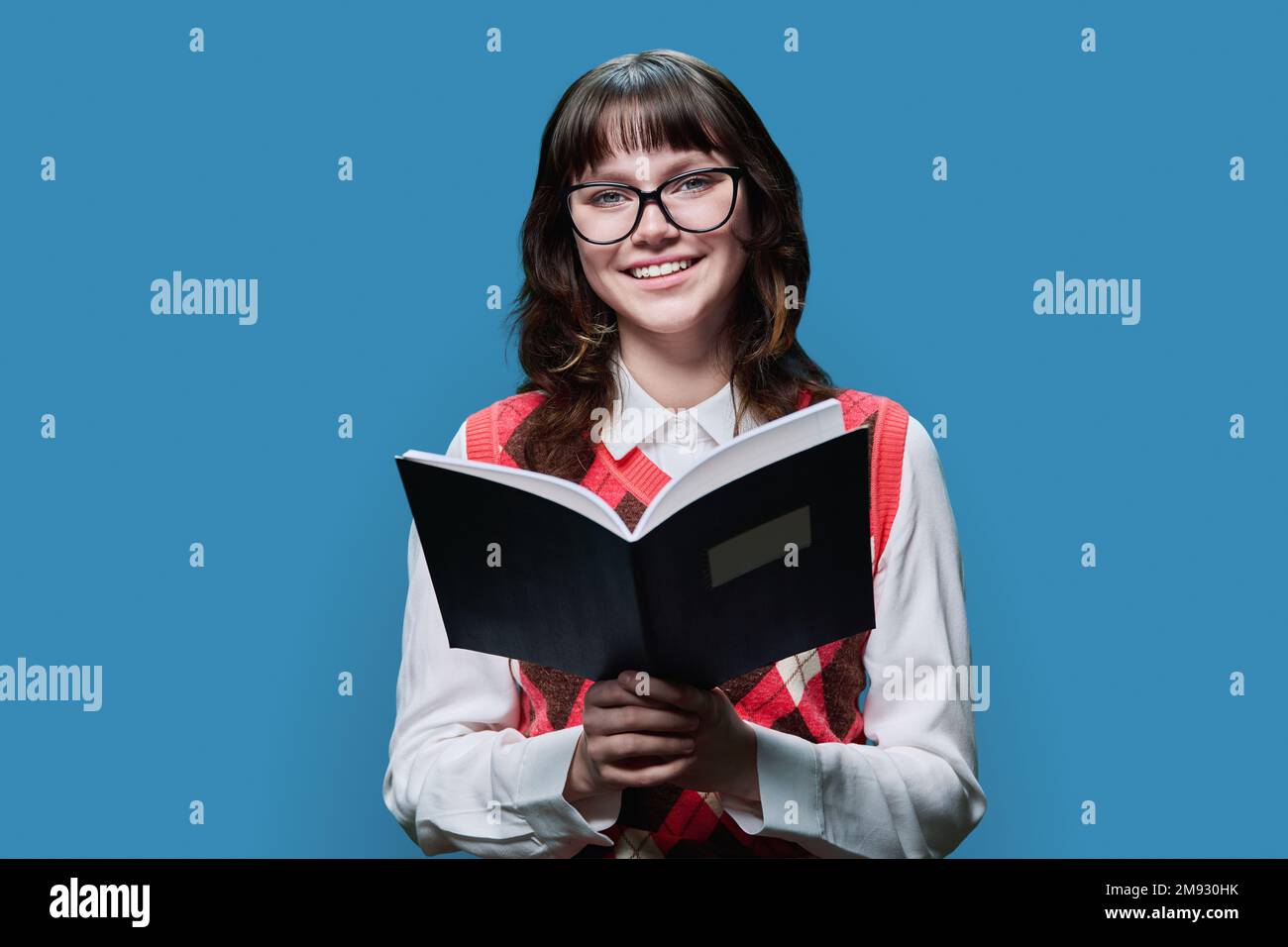College university student reading exercise book, on blue studio ...