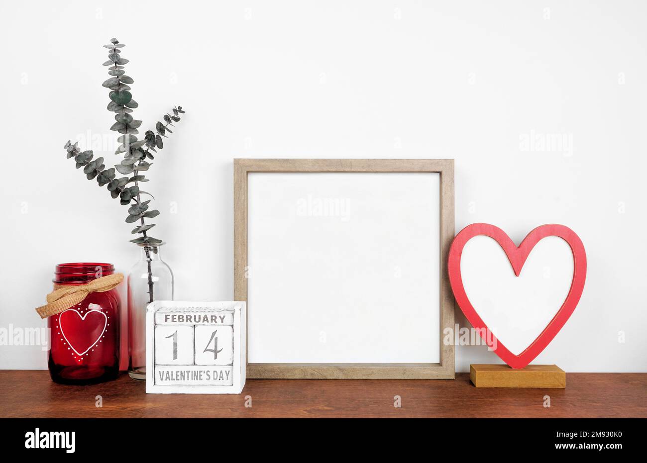 Mock up wood frame with Valentines Day heart decor and calendar. Wood shelf against a white wall. Copy space. Stock Photo