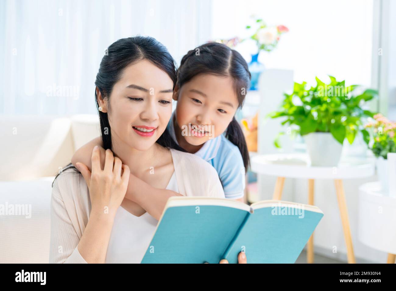 The little girl and her mother read a book together Stock Photo