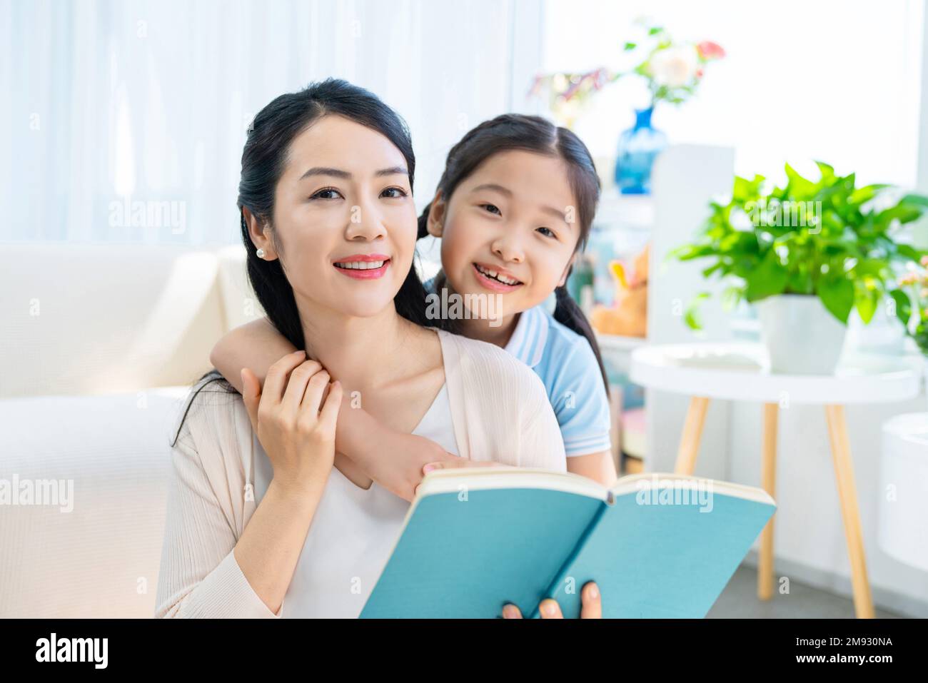 The little girl and her mother read a book together Stock Photo