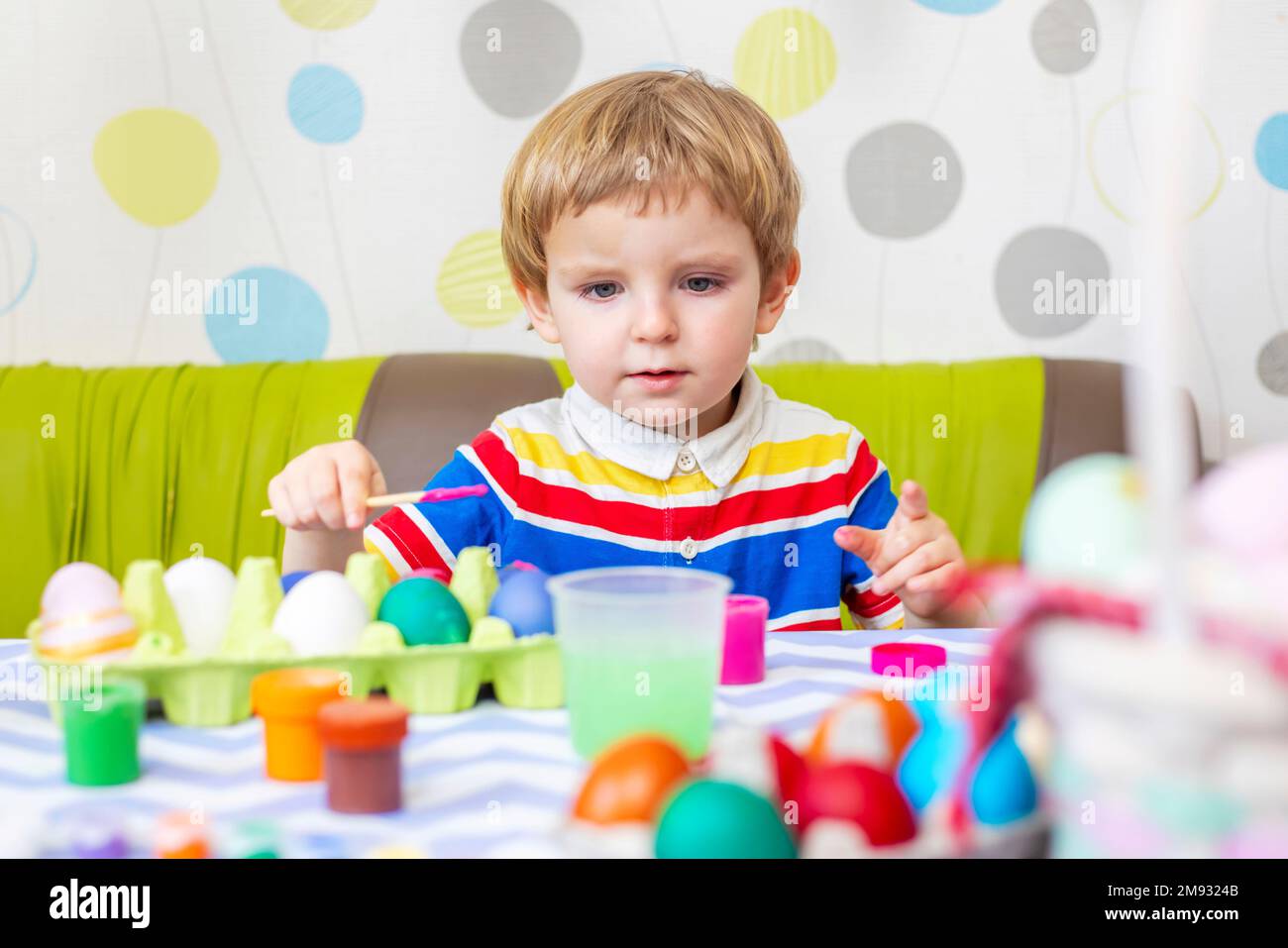 Happy Easter. Boy dyes colorful egg for Easter hunt Stock Photo