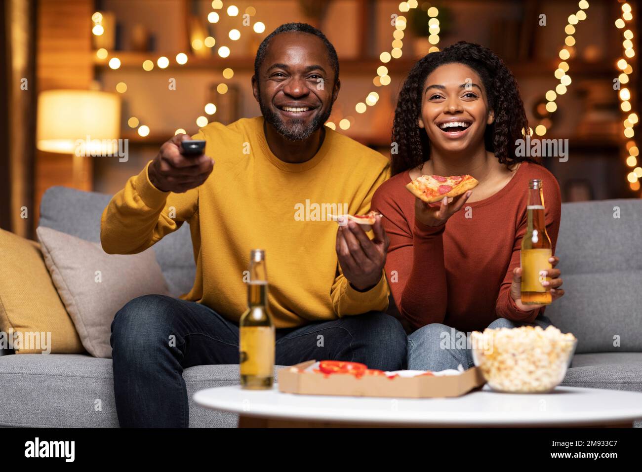 Emotional black couple watching TV together at home Stock Photo - Alamy
