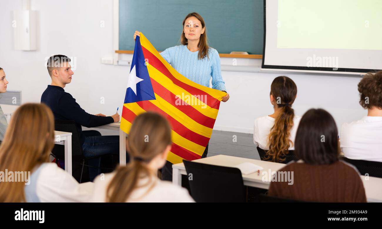 Geography lesson in school class - teacher talks about Catalonia, holding flag in his hands Stock Photo