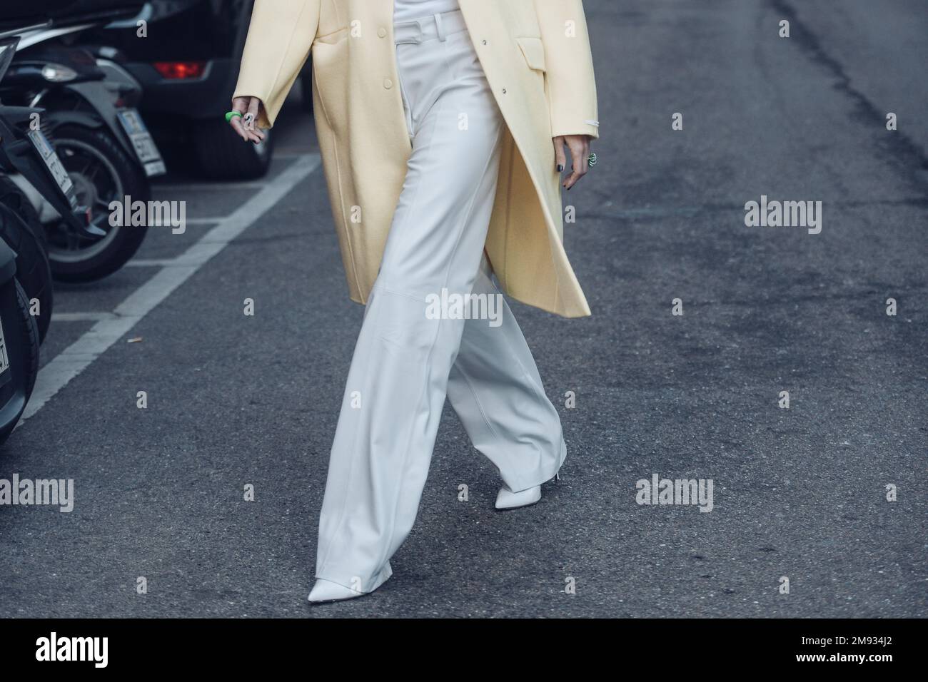 Milan, Italy - February 25, 2022: Female in light palazzo pants with turtleneck and pastel yellow coat over in Milan, Italy. Stock Photo