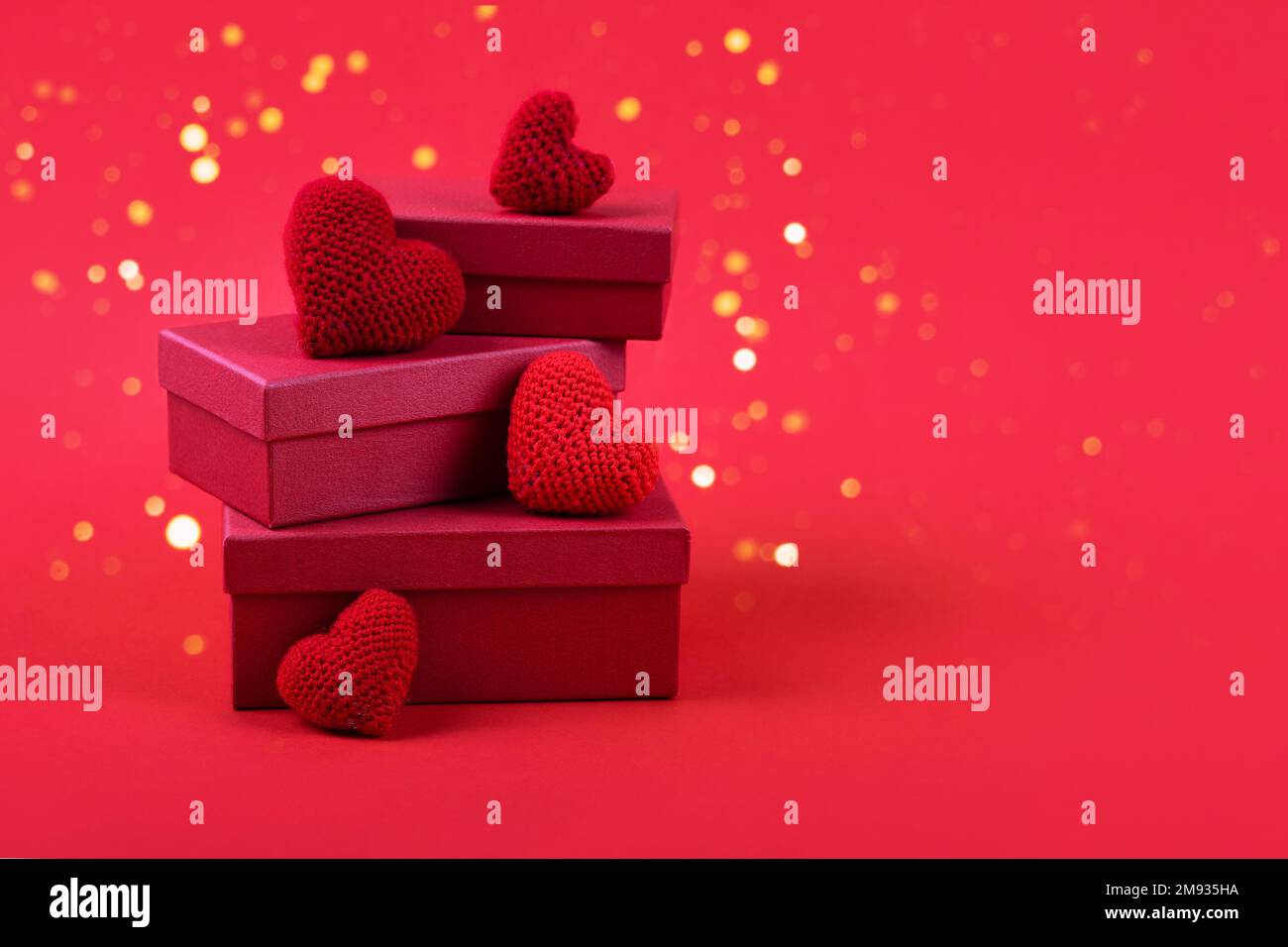Three red gift boxes with crocheted red hearts on a red background with ...