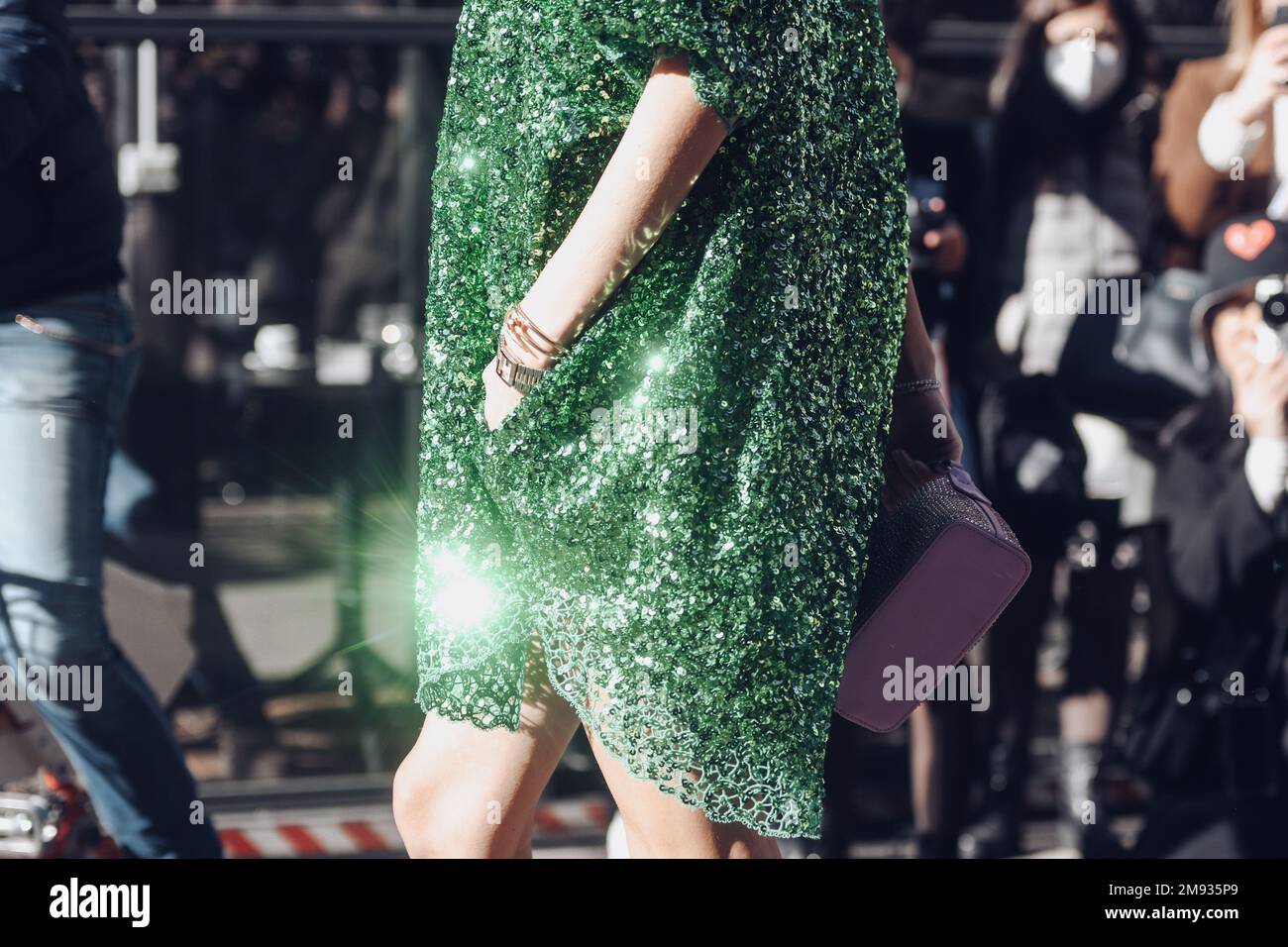 Milan, Italy - February 26, 2022: Female in stylish green dress with shiny sequins holding hand in pocket and carrying lilac handbag. Stock Photo