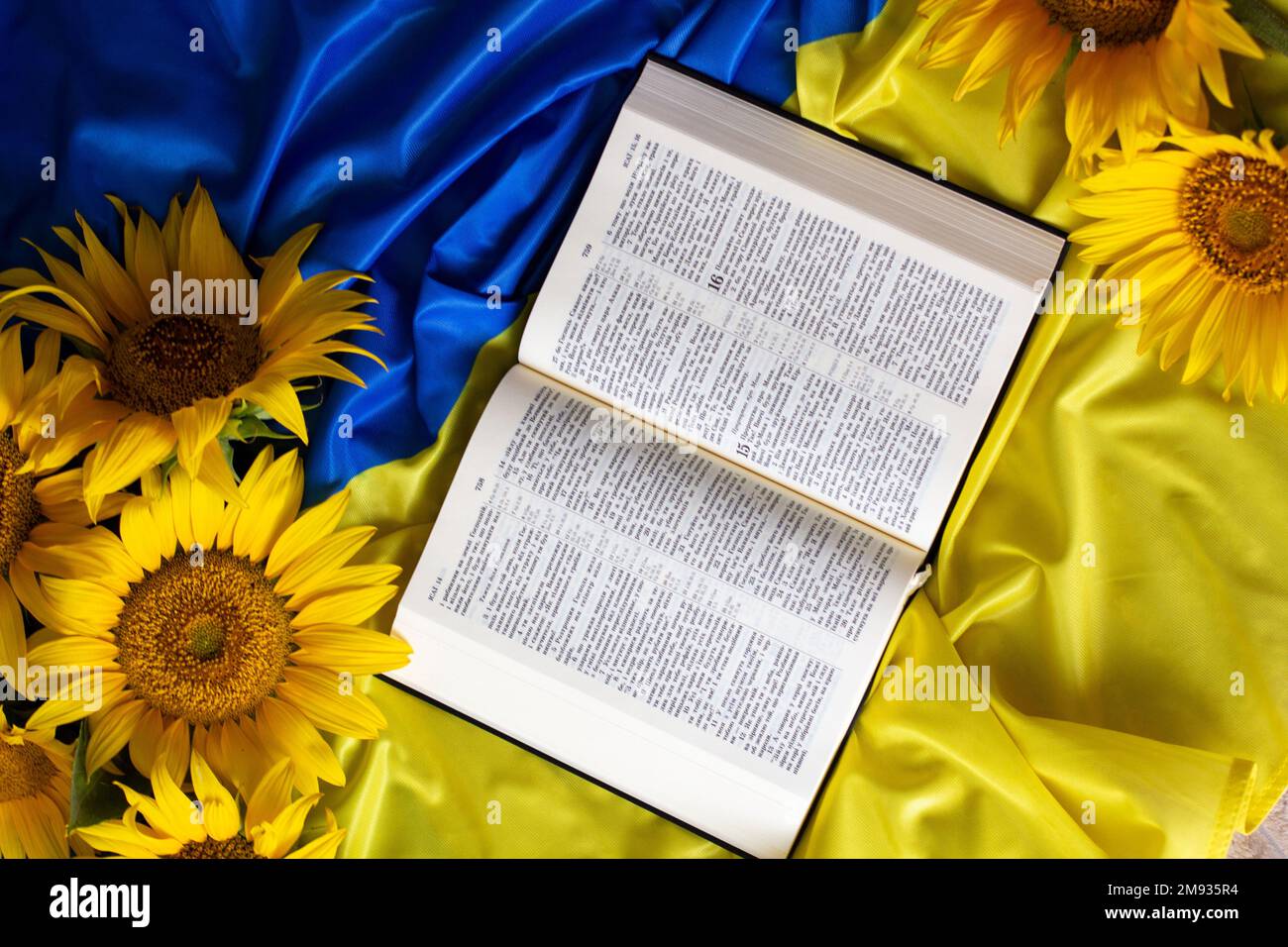 Bible (Holy Writ) and sunflowers on background of flag of Ukraine Stock
