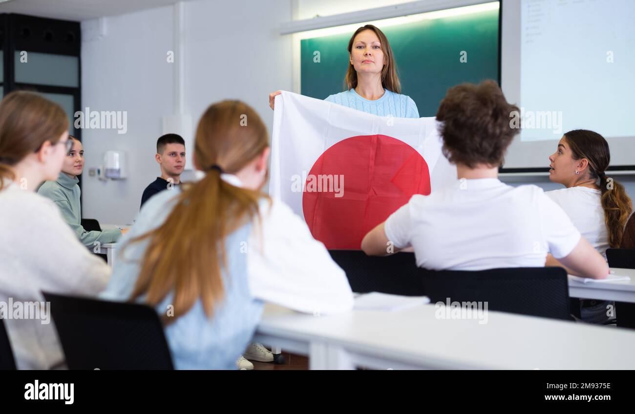 Adult female teacher showing students the flag of Japan Stock Photo Alamy