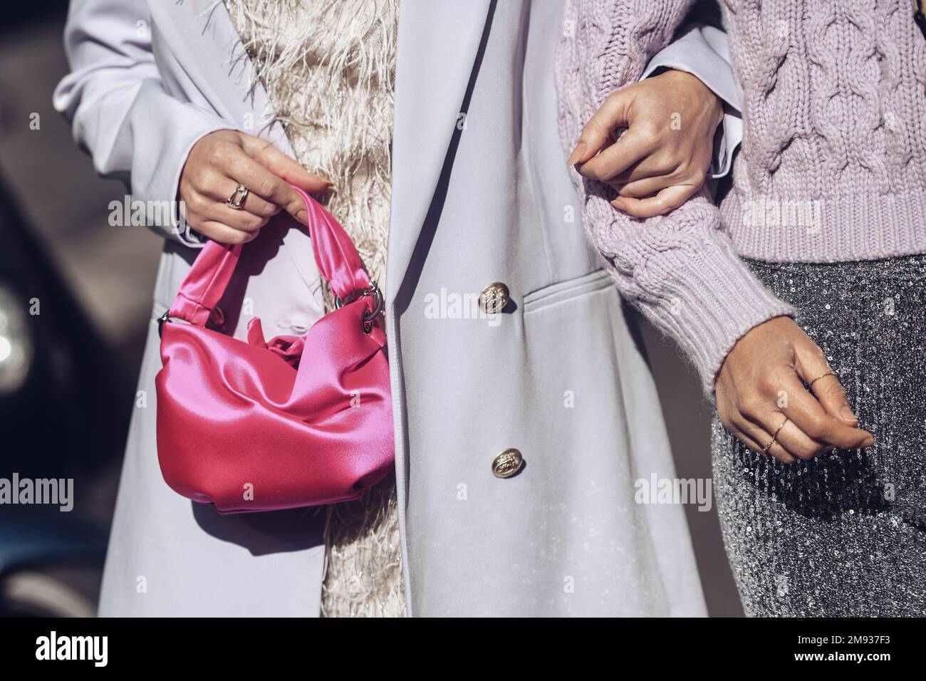 Milan, Italy - February 26, 2022: Woman in stylish outfit with pink bag holding arm of girlfriend. Stock Photo