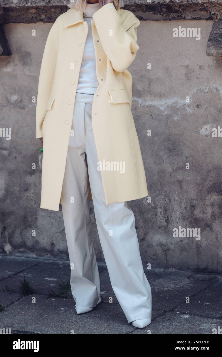 Milan, Italy - February 25, 2022: Crop female in light palazzo pants with turtleneck and pastel yellow coat over strolling in Milan, Italy. Stock Photo